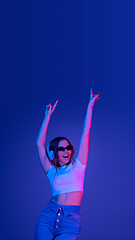 Image showing Caucasian woman\'s portrait isolated on blue studio background in multicolored neon light