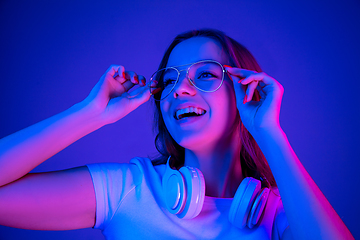 Image showing Caucasian woman\'s portrait isolated on blue studio background in multicolored neon light