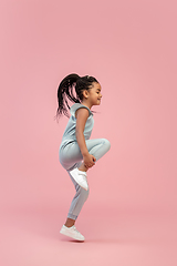 Image showing Happy longhair brunette little girl isolated on pink studio background. Looks happy, cheerful, sincere. Copyspace. Childhood, education, emotions concept