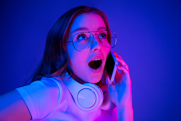 Image showing Caucasian woman\'s portrait isolated on blue studio background in multicolored neon light