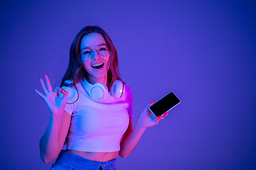 Image showing Caucasian woman\'s portrait isolated on blue studio background in multicolored neon light