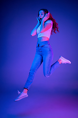 Image showing Caucasian woman\'s portrait isolated on blue studio background in multicolored neon light