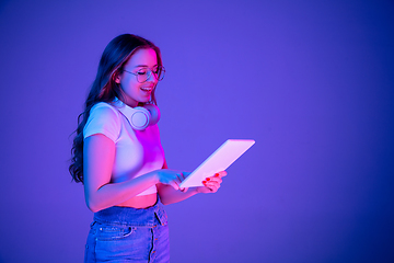 Image showing Caucasian woman\'s portrait isolated on blue studio background in multicolored neon light