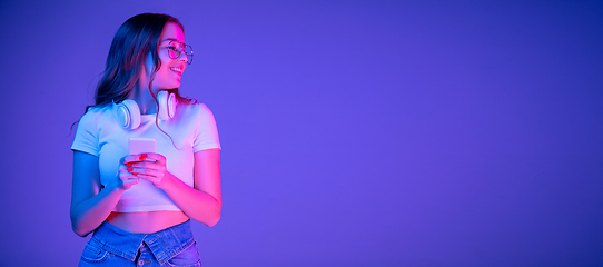 Image showing Caucasian woman\'s portrait isolated on blue studio background in multicolored neon light