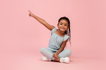 Image showing Happy longhair brunette little girl isolated on pink studio background. Looks happy, cheerful, sincere. Copyspace. Childhood, education, emotions concept