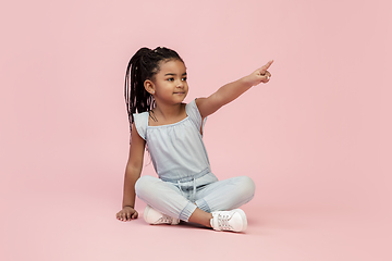 Image showing Happy longhair brunette little girl isolated on pink studio background. Looks happy, cheerful, sincere. Copyspace. Childhood, education, emotions concept