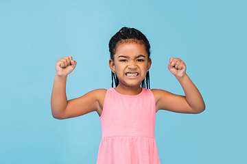 Image showing Happy longhair brunette little girl isolated on blue studio background. Looks happy, cheerful, sincere. Copyspace. Childhood, education, emotions concept