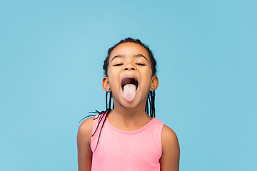 Image showing Happy longhair brunette little girl isolated on blue studio background. Looks happy, cheerful, sincere. Copyspace. Childhood, education, emotions concept