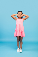 Image showing Happy longhair brunette little girl isolated on blue studio background. Looks happy, cheerful, sincere. Copyspace. Childhood, education, emotions concept