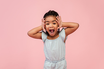 Image showing Happy longhair brunette little girl isolated on pink studio background. Looks happy, cheerful, sincere. Copyspace. Childhood, education, emotions concept