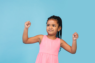 Image showing Happy longhair brunette little girl isolated on blue studio background. Looks happy, cheerful, sincere. Copyspace. Childhood, education, emotions concept