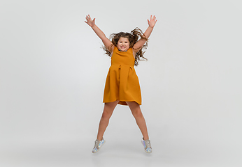 Image showing Happy caucasian little girl isolated on studio background. Looks happy, cheerful, sincere. Copyspace. Childhood, education, emotions concept