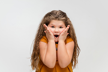 Image showing Happy caucasian little girl isolated on studio background. Looks happy, cheerful, sincere. Copyspace. Childhood, education, emotions concept
