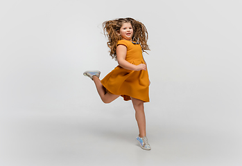 Image showing Happy caucasian little girl isolated on studio background. Looks happy, cheerful, sincere. Copyspace. Childhood, education, emotions concept