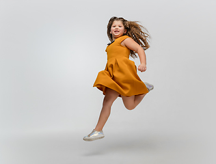 Image showing Happy caucasian little girl isolated on studio background. Looks happy, cheerful, sincere. Copyspace. Childhood, education, emotions concept