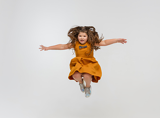 Image showing Happy caucasian little girl isolated on studio background. Looks happy, cheerful, sincere. Copyspace. Childhood, education, emotions concept