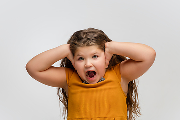 Image showing Happy caucasian little girl isolated on studio background. Looks happy, cheerful, sincere. Copyspace. Childhood, education, emotions concept