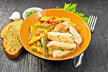 Image showing Chicken with stewed zucchini in plate on dark board