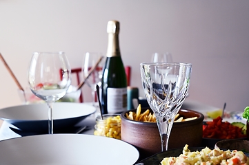 Image showing bottle of wine, empty wineglasses and side dishes on the table