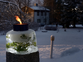 Image showing a lit outdoor garden candle in the courtyard on Christmas