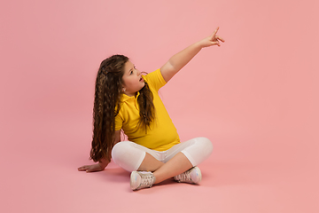 Image showing Happy caucasian little girl isolated on studio background. Looks happy, cheerful, sincere. Copyspace. Childhood, education, emotions concept