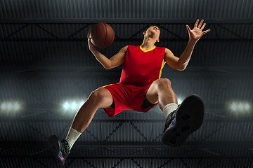 Image showing Young professional basketball player in action, motion isolated on black background, look from the bottom. Concept of sport, movement, energy and dynamic.