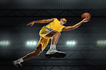 Image showing Young professional basketball player in action, motion isolated on black background, look from the bottom. Concept of sport, movement, energy and dynamic.