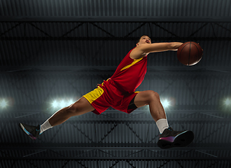 Image showing Young professional basketball player in action, motion isolated on black background, look from the bottom. Concept of sport, movement, energy and dynamic.