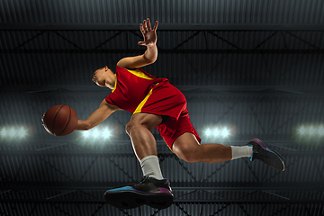 Image showing Young professional basketball player in action, motion isolated on black background, look from the bottom. Concept of sport, movement, energy and dynamic.