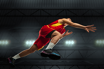 Image showing Young professional basketball player in action, motion isolated on black background, look from the bottom. Concept of sport, movement, energy and dynamic.