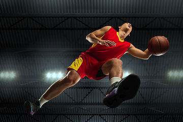 Image showing Young professional basketball player in action, motion isolated on black background, look from the bottom. Concept of sport, movement, energy and dynamic.