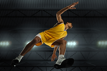 Image showing Young professional basketball player in action, motion isolated on black background, look from the bottom. Concept of sport, movement, energy and dynamic.