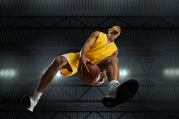 Image showing Young professional basketball player in action, motion isolated on black background, look from the bottom. Concept of sport, movement, energy and dynamic.