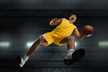 Image showing Young professional basketball player in action, motion isolated on black background, look from the bottom. Concept of sport, movement, energy and dynamic.