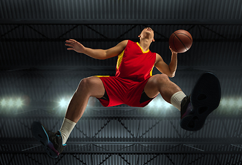 Image showing Young professional basketball player in action, motion isolated on black background, look from the bottom. Concept of sport, movement, energy and dynamic.