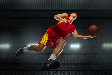 Image showing Young professional basketball player in action, motion isolated on black background, look from the bottom. Concept of sport, movement, energy and dynamic.