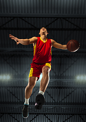 Image showing Young professional basketball player in action, motion isolated on black background, look from the bottom. Concept of sport, movement, energy and dynamic.