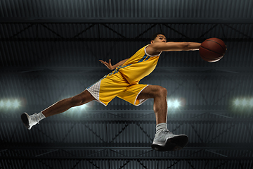 Image showing Young professional basketball player in action, motion isolated on black background, look from the bottom. Concept of sport, movement, energy and dynamic.