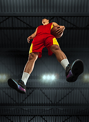 Image showing Young professional basketball player in action, motion isolated on black background, look from the bottom. Concept of sport, movement, energy and dynamic.