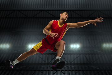 Image showing Young professional basketball player in action, motion isolated on black background, look from the bottom. Concept of sport, movement, energy and dynamic.