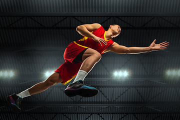 Image showing Young professional basketball player in action, motion isolated on black background, look from the bottom. Concept of sport, movement, energy and dynamic.