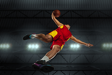 Image showing Young professional basketball player in action, motion isolated on black background, look from the bottom. Concept of sport, movement, energy and dynamic.