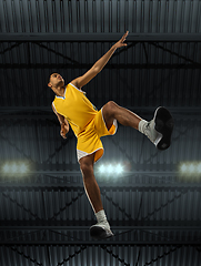 Image showing Young professional basketball player in action, motion isolated on black background, look from the bottom. Concept of sport, movement, energy and dynamic.