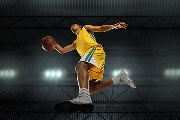 Image showing Young professional basketball player in action, motion isolated on black background, look from the bottom. Concept of sport, movement, energy and dynamic.