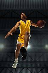 Image showing Young professional basketball player in action, motion isolated on black background, look from the bottom. Concept of sport, movement, energy and dynamic.