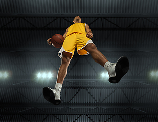 Image showing Young professional basketball player in action, motion isolated on black background, look from the bottom. Concept of sport, movement, energy and dynamic.