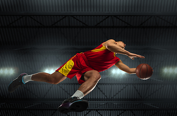 Image showing Young professional basketball player in action, motion isolated on black background, look from the bottom. Concept of sport, movement, energy and dynamic.