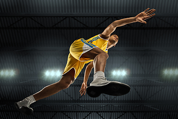 Image showing Young professional basketball player in action, motion isolated on black background, look from the bottom. Concept of sport, movement, energy and dynamic.