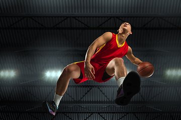 Image showing Young professional basketball player in action, motion isolated on black background, look from the bottom. Concept of sport, movement, energy and dynamic.