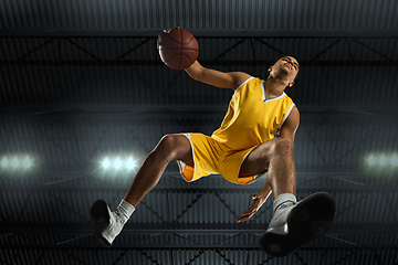 Image showing Young professional basketball player in action, motion isolated on black background, look from the bottom. Concept of sport, movement, energy and dynamic.